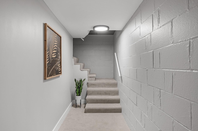 staircase with carpet floors, concrete block wall, and baseboards