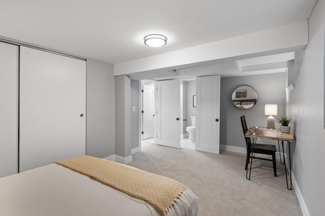 bedroom with a closet, light colored carpet, connected bathroom, and baseboards