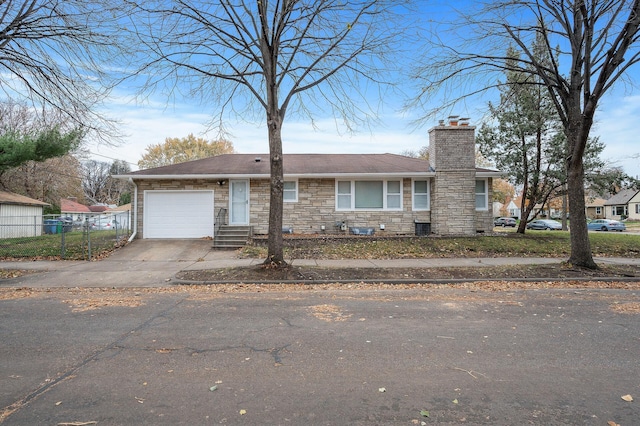 view of front facade featuring a garage, fence, driveway, stone siding, and a chimney