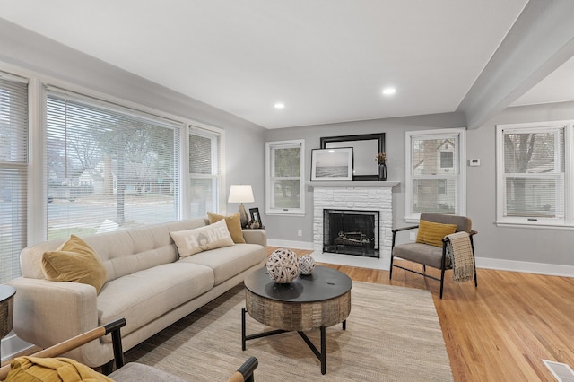 living room with light wood-style floors, visible vents, a fireplace, and baseboards