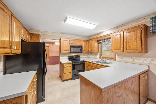 kitchen with wallpapered walls, a peninsula, a sink, black appliances, and light countertops