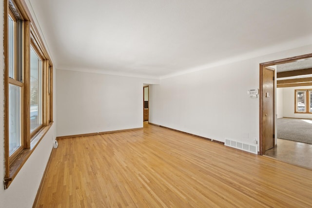 unfurnished room featuring light wood-type flooring, visible vents, and baseboards