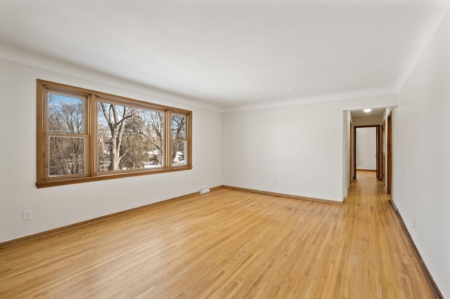 spare room with baseboards and light wood-style floors