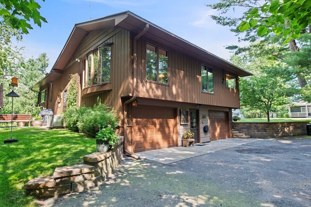 exterior space with a garage, aphalt driveway, and a front yard