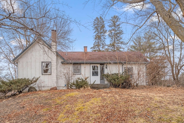 view of front of property with entry steps, roof with shingles, and a chimney