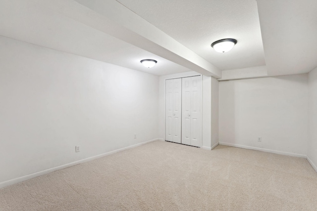 unfurnished bedroom with carpet floors, a closet, a textured ceiling, and baseboards