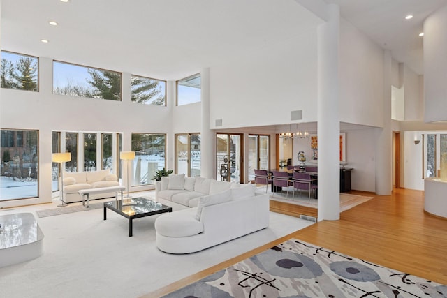 living room featuring visible vents, a chandelier, light wood-type flooring, recessed lighting, and a towering ceiling