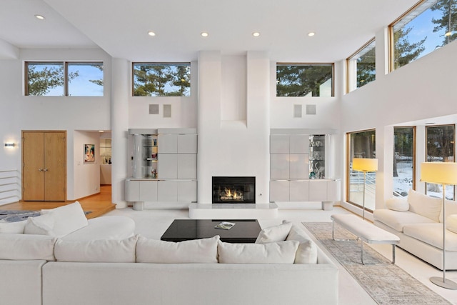 living room featuring a glass covered fireplace, wood finished floors, and recessed lighting