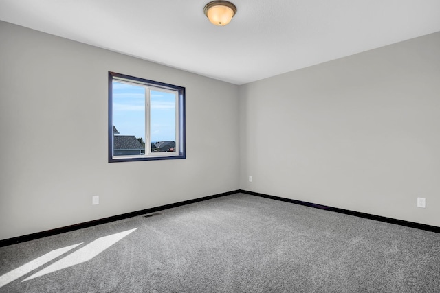 spare room featuring carpet, visible vents, and baseboards