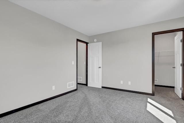 unfurnished bedroom featuring baseboards, visible vents, a walk in closet, and carpet flooring