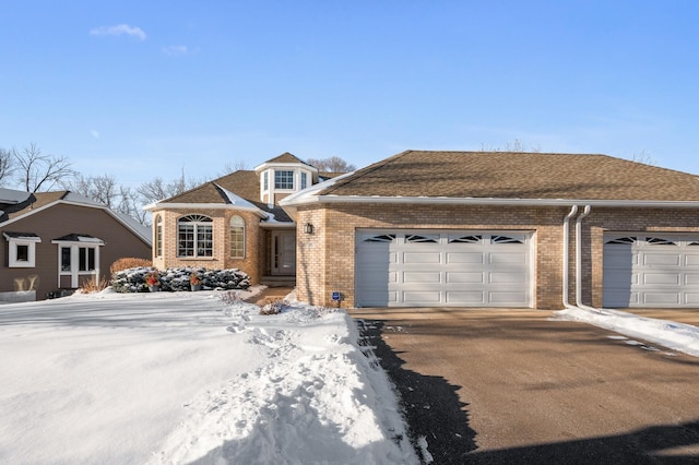 view of front of property with driveway, roof with shingles, a garage, and brick siding