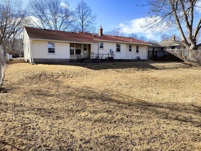 rear view of house with a chimney and fence