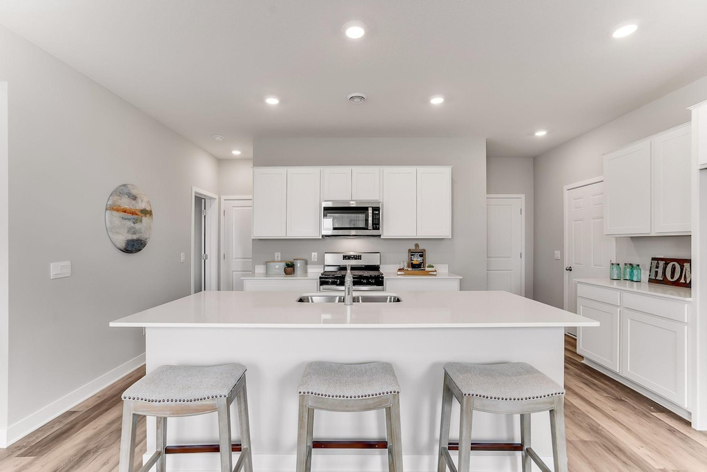 kitchen with light countertops, appliances with stainless steel finishes, and an island with sink