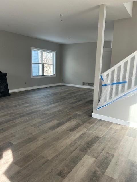 unfurnished living room with baseboards, visible vents, and wood finished floors