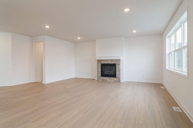 unfurnished living room with light wood-style floors, recessed lighting, visible vents, and a stone fireplace