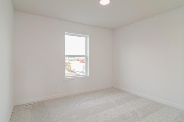 unfurnished room featuring baseboards, visible vents, and light colored carpet