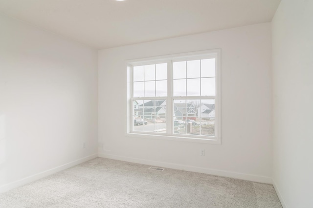 unfurnished room with carpet floors, visible vents, and baseboards