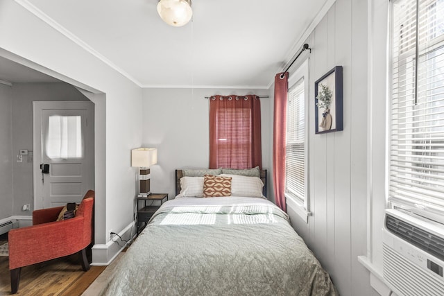 bedroom featuring ornamental molding, cooling unit, baseboards, and wood finished floors