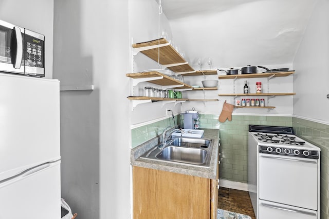 kitchen featuring a sink, open shelves, white appliances, tile walls, and wainscoting