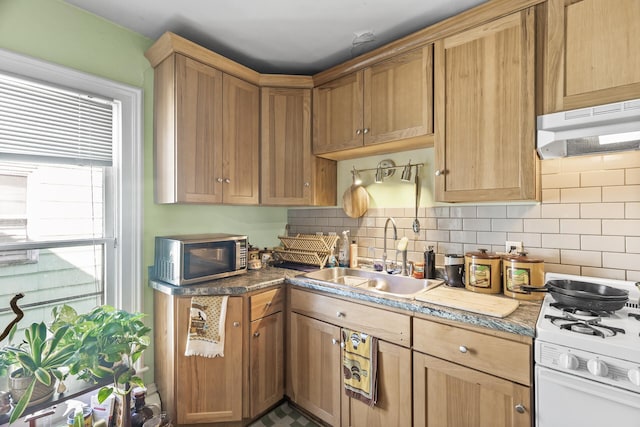 kitchen featuring tasteful backsplash, stainless steel microwave, white gas stove, under cabinet range hood, and a sink