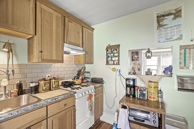 kitchen featuring under cabinet range hood, a sink, light countertops, decorative backsplash, and white range with gas stovetop