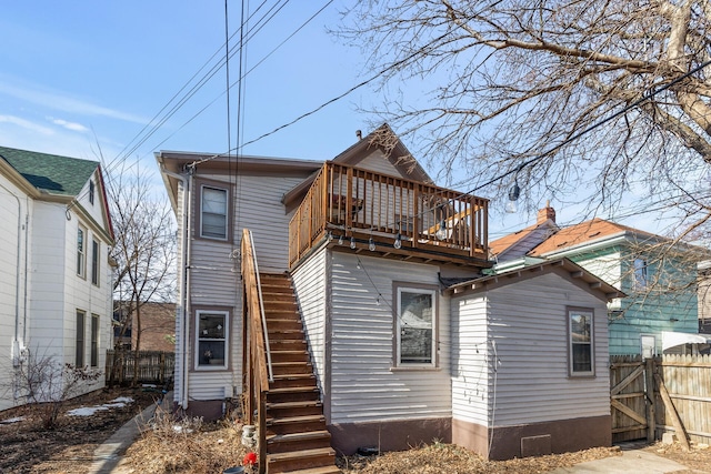 rear view of house featuring a gate, stairway, and fence