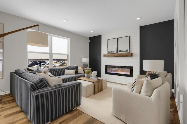 living area with a large fireplace, light wood finished floors, and recessed lighting