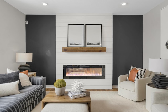 living area featuring recessed lighting, a large fireplace, baseboards, and wood finished floors