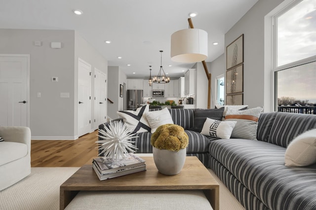 living room with light wood-type flooring, an inviting chandelier, baseboards, and recessed lighting