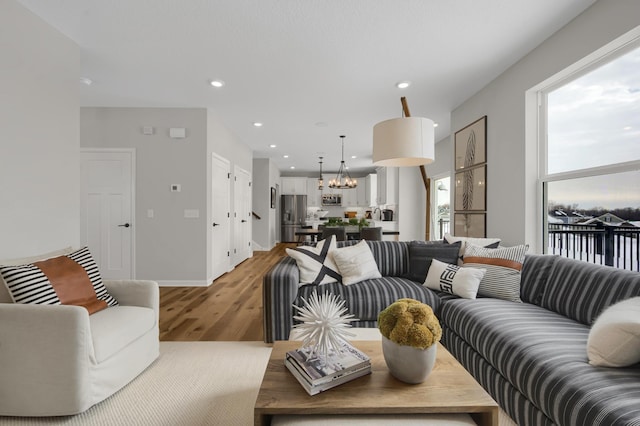 living room featuring light wood-style flooring, a chandelier, baseboards, and recessed lighting