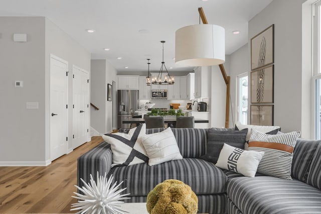 living room featuring a notable chandelier, recessed lighting, stairway, light wood-style flooring, and baseboards