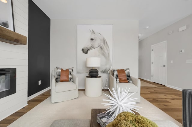 living area featuring a fireplace, wood finished floors, and baseboards