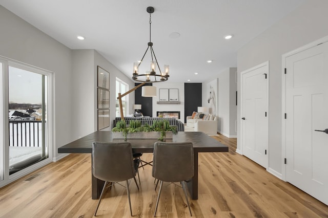 dining area with a chandelier, recessed lighting, a fireplace, and light wood-style floors