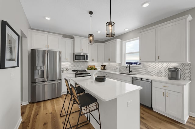 kitchen with a center island, stainless steel appliances, light wood-style floors, white cabinetry, and a sink