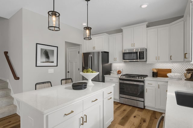 kitchen with light wood-style floors, appliances with stainless steel finishes, and decorative backsplash