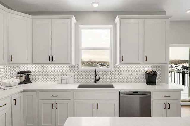 kitchen featuring dishwasher, plenty of natural light, a sink, and white cabinetry