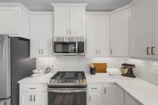 kitchen with stainless steel appliances, white cabinets, light countertops, and backsplash