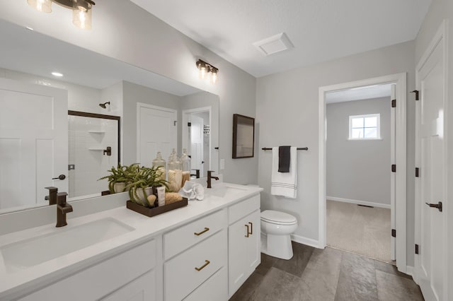 bathroom featuring double vanity, tiled shower, a sink, and toilet