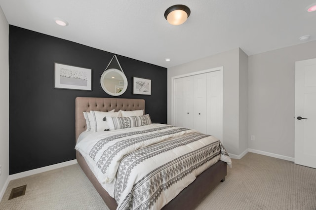 bedroom with baseboards, visible vents, a closet, and light colored carpet