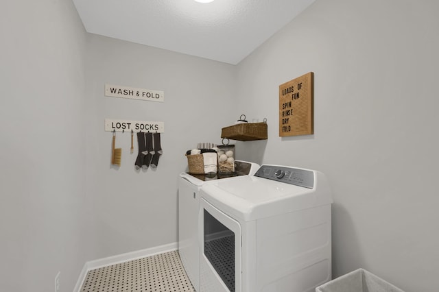 washroom featuring washing machine and clothes dryer, a textured ceiling, laundry area, baseboards, and tile patterned floors