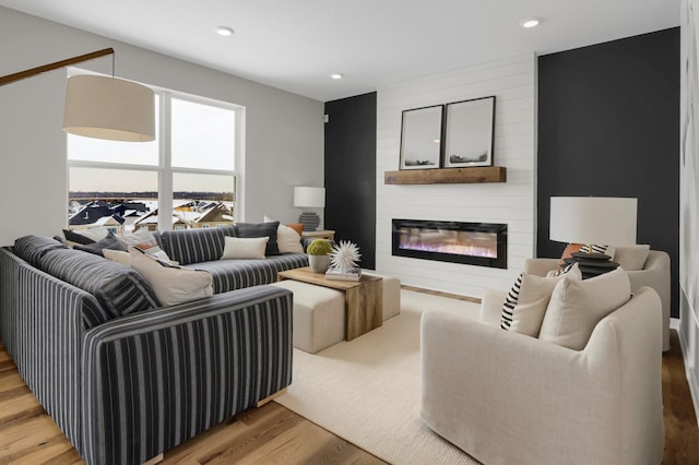 living area featuring recessed lighting, a large fireplace, and wood finished floors