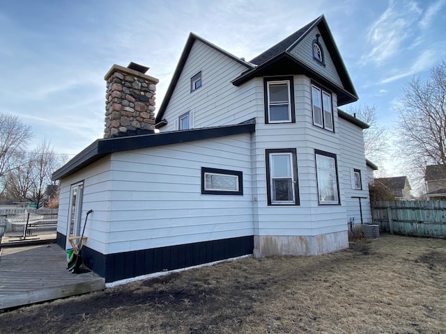 view of side of home featuring a chimney and fence