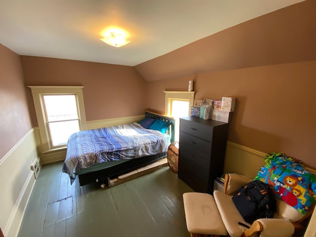 bedroom with vaulted ceiling, a wainscoted wall, and wood-type flooring