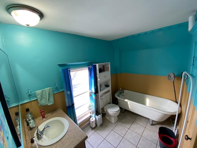 bathroom featuring tile patterned flooring, toilet, vanity, and a freestanding bath