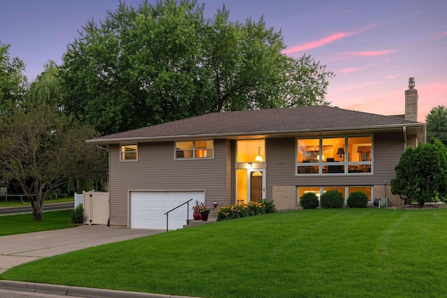 raised ranch with a garage, a front yard, driveway, and a chimney