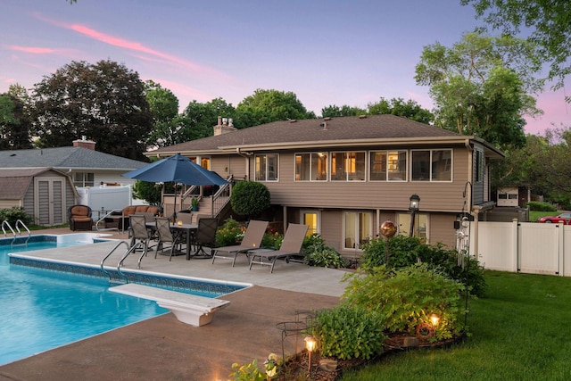 back of property with a fenced backyard, an outdoor structure, a fenced in pool, a shed, and a patio area