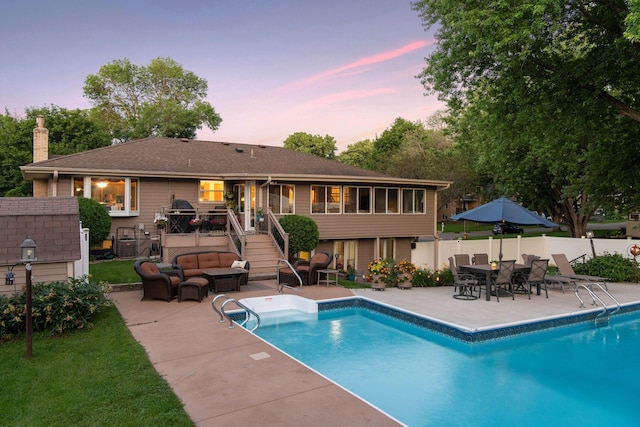 pool at dusk with a fenced in pool, fence, a deck, a patio area, and an outdoor living space