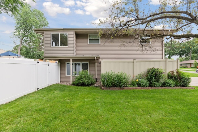 rear view of property featuring fence and a lawn