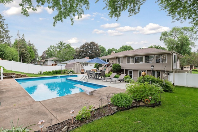 view of swimming pool with a lawn, a fenced in pool, a patio, a fenced backyard, and an outdoor structure