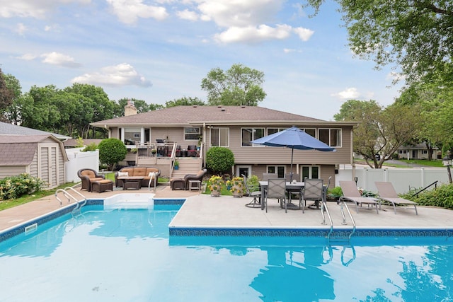 view of swimming pool with a storage unit, outdoor lounge area, fence, and a fenced in pool